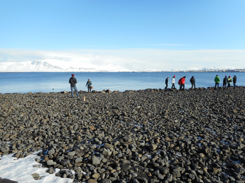 παραλία με μαύρο βότσαλο και κόσμο να περπατά στο λιμάνι του Ρέικιαβικ