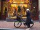 Γυναίκα με λευκό μπερέ και ποδήλατο στους "εννέα δρόμους" στο Άμστερνταμ